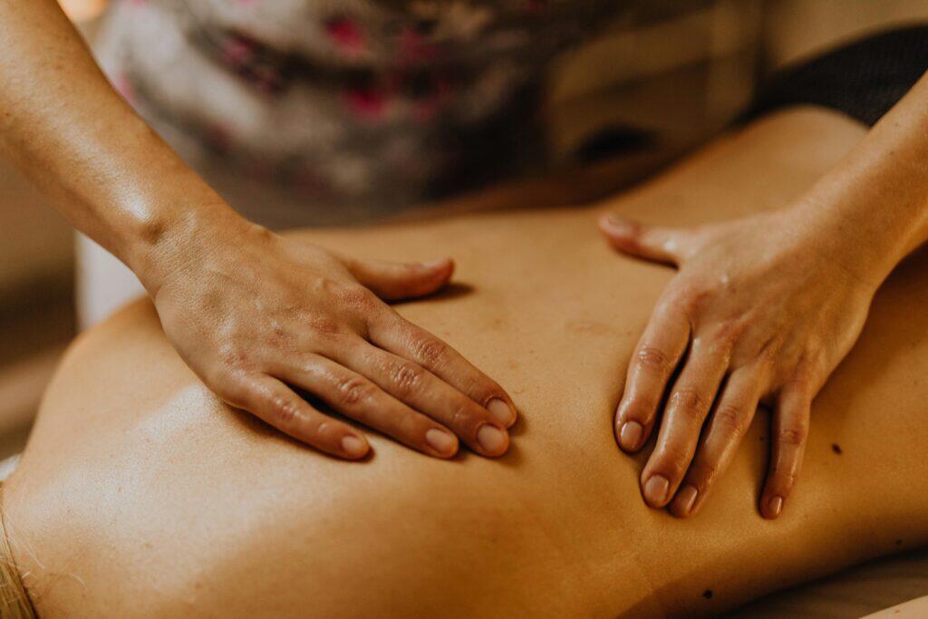 Two hands giving a deep tissue back massage in a calm spa setting, warm light, professional therapist