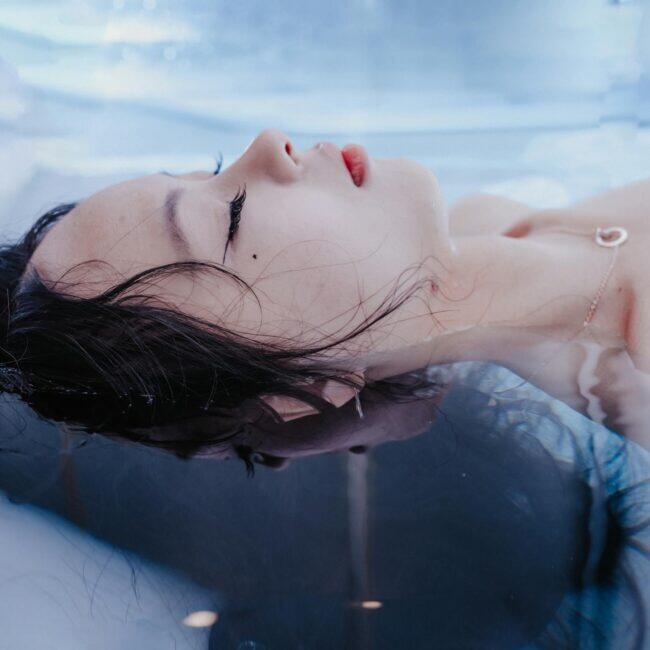 A person floating on their back in a pool with eyes closed, hair spreading in the water, illustrating the calm of an open pool float