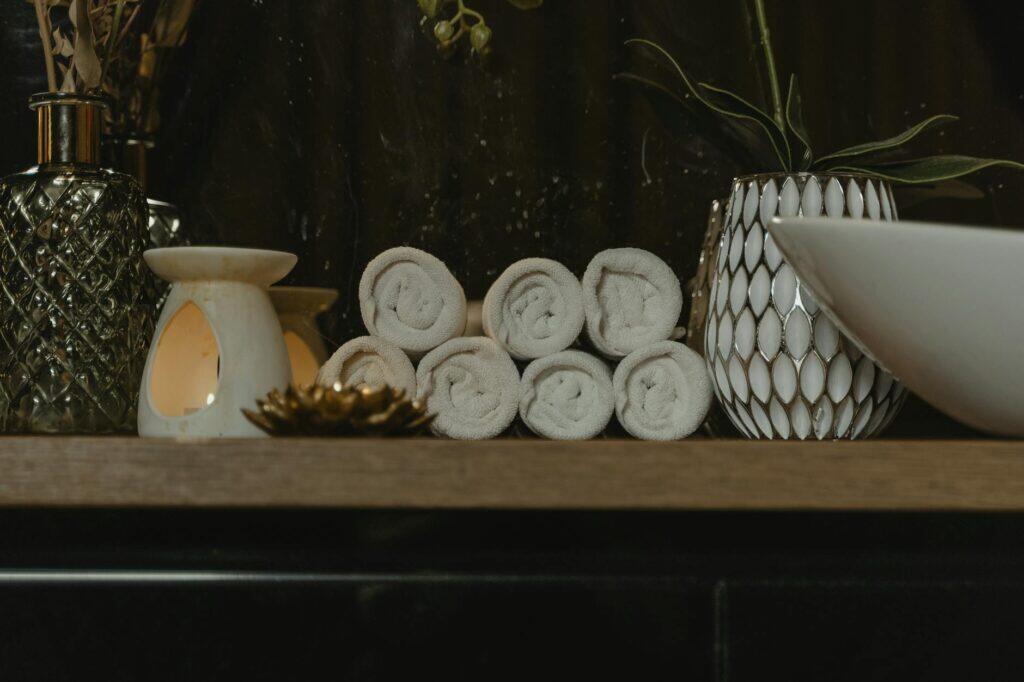 Rolled spa towels with candlelight in a serene treatment setting, evoking the calm of a combined sauna and massage session