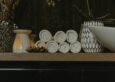 Rolled spa towels with candlelight in a serene treatment setting, evoking the calm of a combined sauna and massage session
