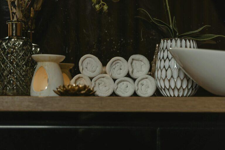 Rolled spa towels with candlelight in a serene treatment setting, evoking the calm of a combined sauna and massage session