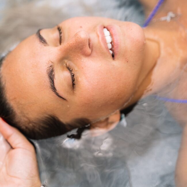 Woman floating peacefully with eyes closed during a float therapy session