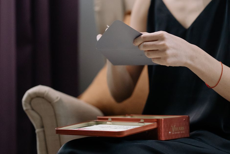 A person holding a small wrapped gift and a card at home