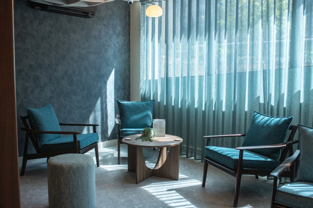 The calm relaxation lounge at being in St Albans, with teal armchairs and soft daylight